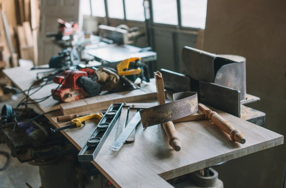Werkbank mit Werkzeugen und Säge in einer staubigen Werkstatt