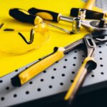 Werkzeug und Schutzbrille auf gelbem Lochbrett