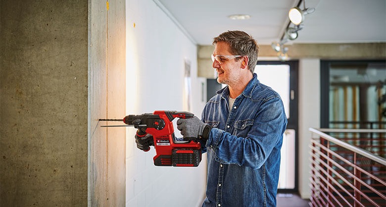 Ein Mann bohrt mit einer Bohrmaschine in eine Wand