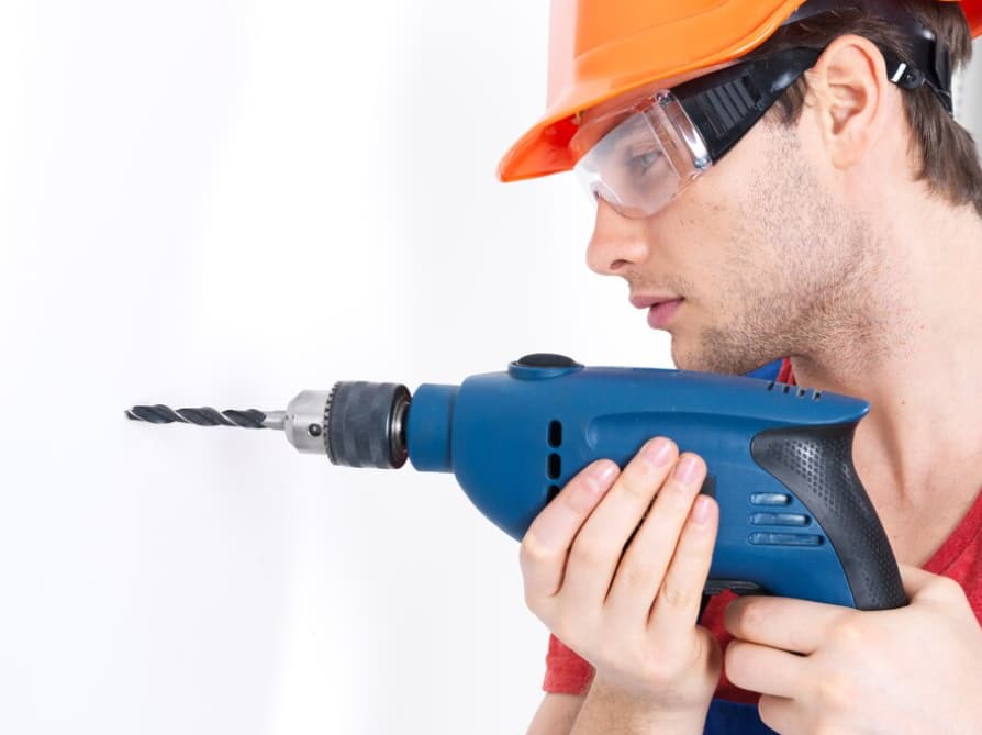 Mann untersucht genau einen an Bohrmaschine befestigten Bohrer