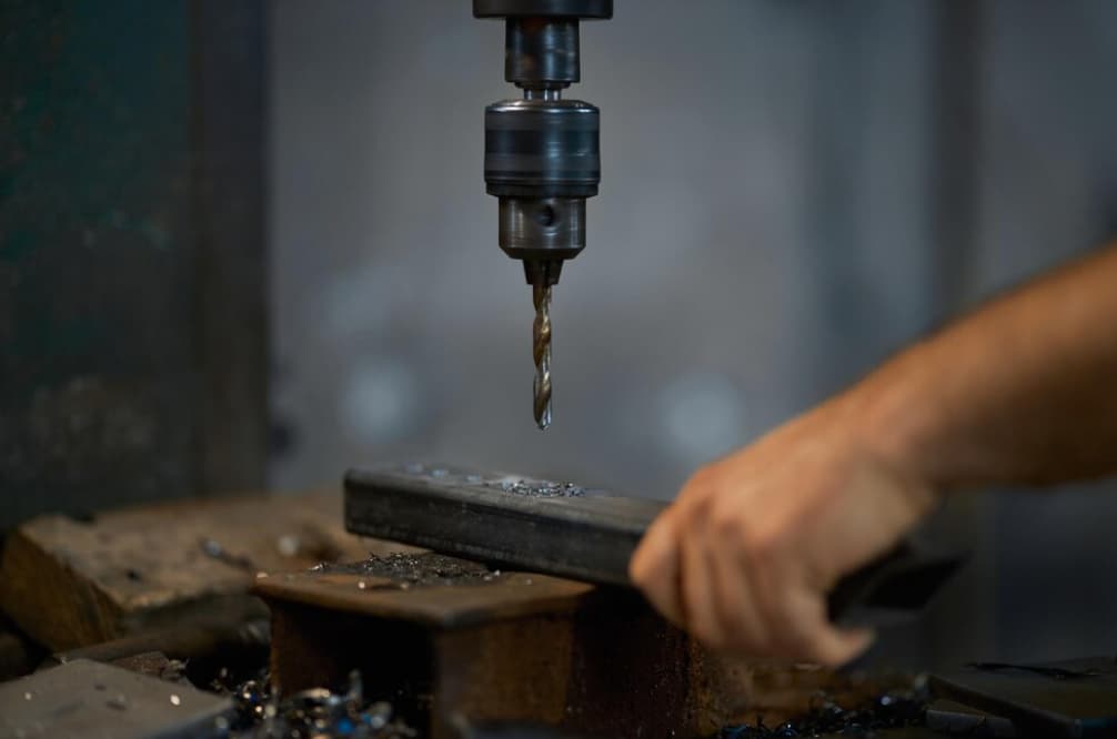 Eine Bohrmaschine bearbeitet ein Metallstück in einer Werkstatt