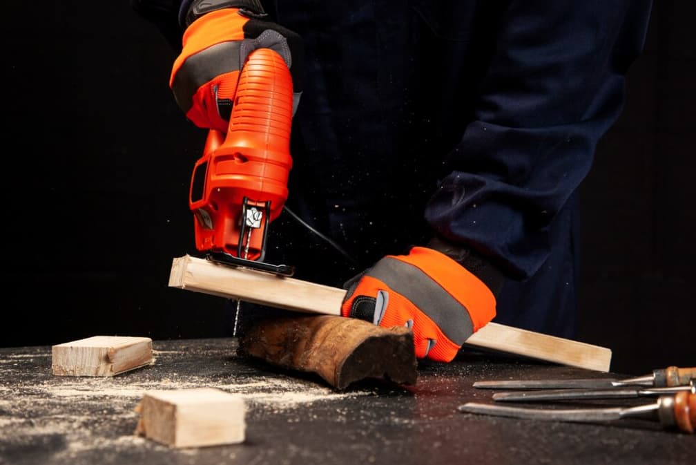 Person schneidet Holz mit roter Säbelsäge